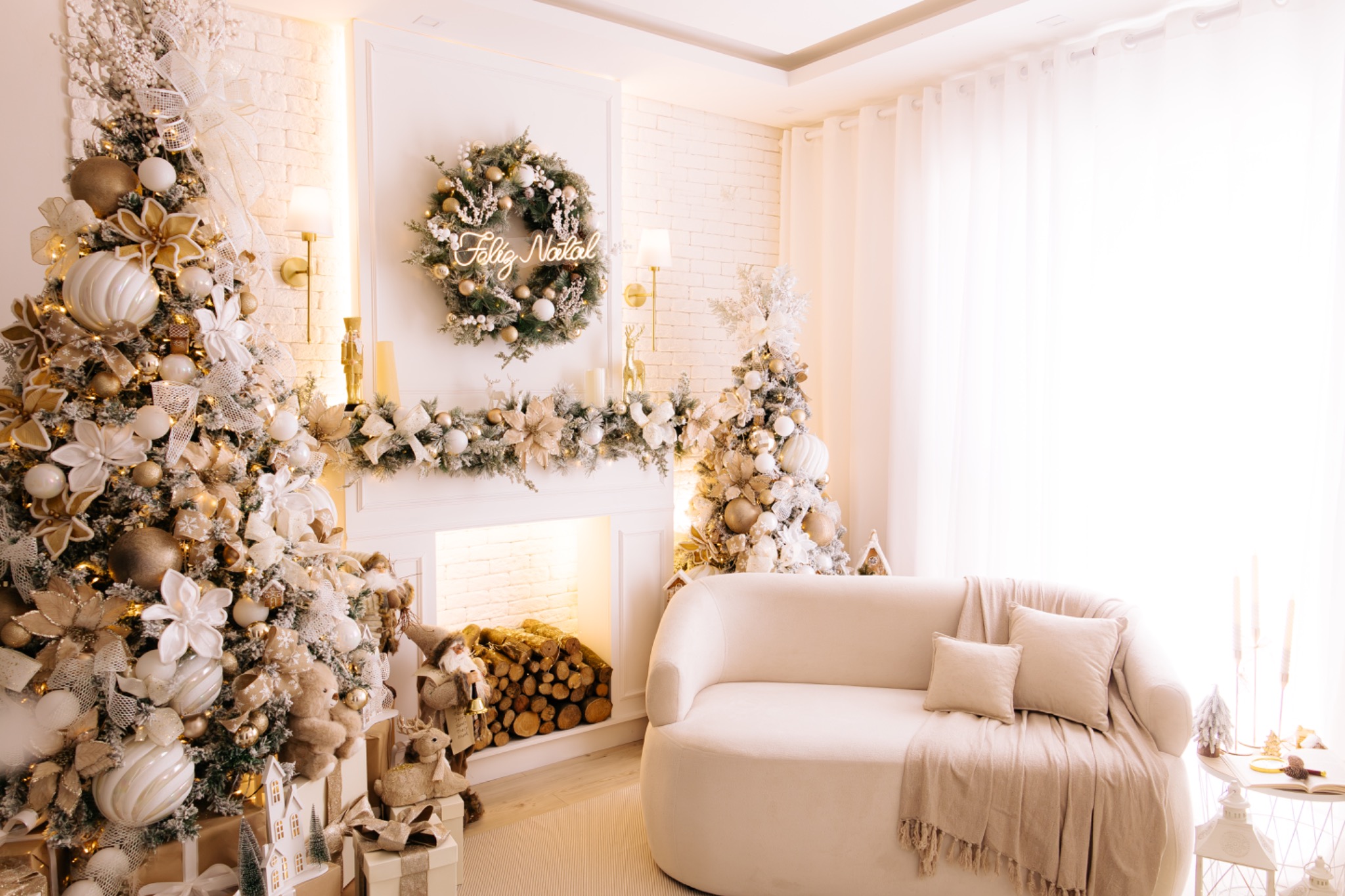 Visão ampla do cenário principal de Natal, com árvores, lareira e sofá claro